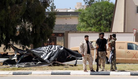 Soldados libios en Sirte, ante un cartel del Estado Islámico derribado.