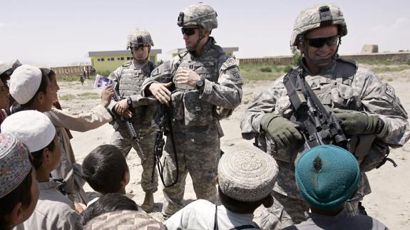 Grupo de escolares saludan a militares estadounidenses.