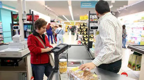 Una mujer realizando la compra en un supermercado. 