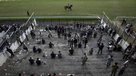 Varios aficionados esperan a una carrera de caballos. 