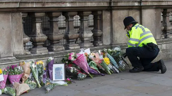 Un policía coloca flores en honor a una de las víctimas del ataque en Londres.