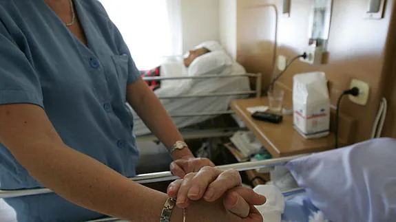 Una enfermera da la mano a un anciano hospitalizado en una clínica de Álava.