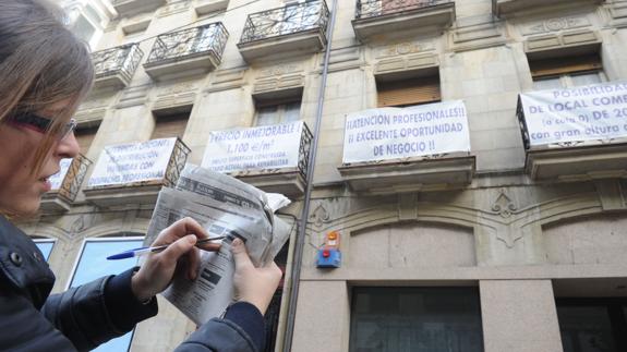 Una mujer busca viviendas en un periódico. 