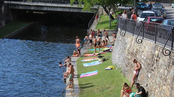 Unos jóvenes se disponen a meterse en el agua en la playa fluvial.