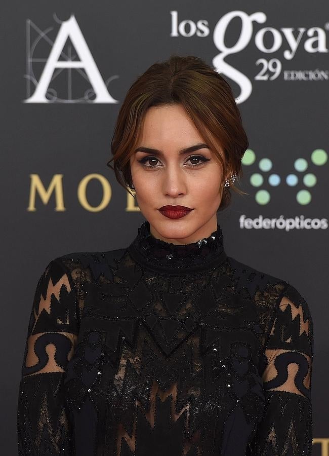 Megan Montaner con moño bajo peinado con raya en medio y mechones sueltos en los Premios Goya 2015, que combinó con labios 'vamp'.