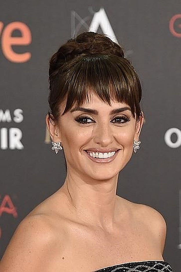 Penélope Cruz con moño alto trenzado y flequillo postizo.