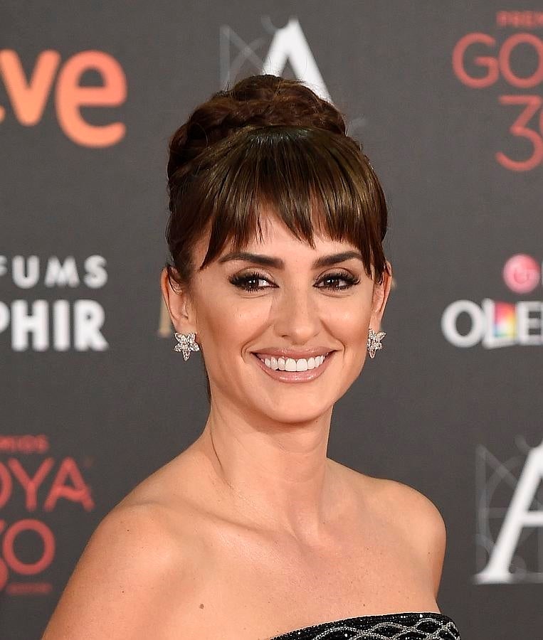 Penélope Cruz brilló en la alfombra roja de los Goya 2016 con un look beauty muy favorecedor y que recordaba a Audrey Hepburn. La actriz recogió su larga melena en un moño alto rodeado por una trenza y lució flequillo postizo. El maquillaje, de Lancôme, resaltaba su belleza natural y centraba su atención en la mirada: ojos enmarcados con eyeliner negro y pestañas XL. En la boca, un tono nude.