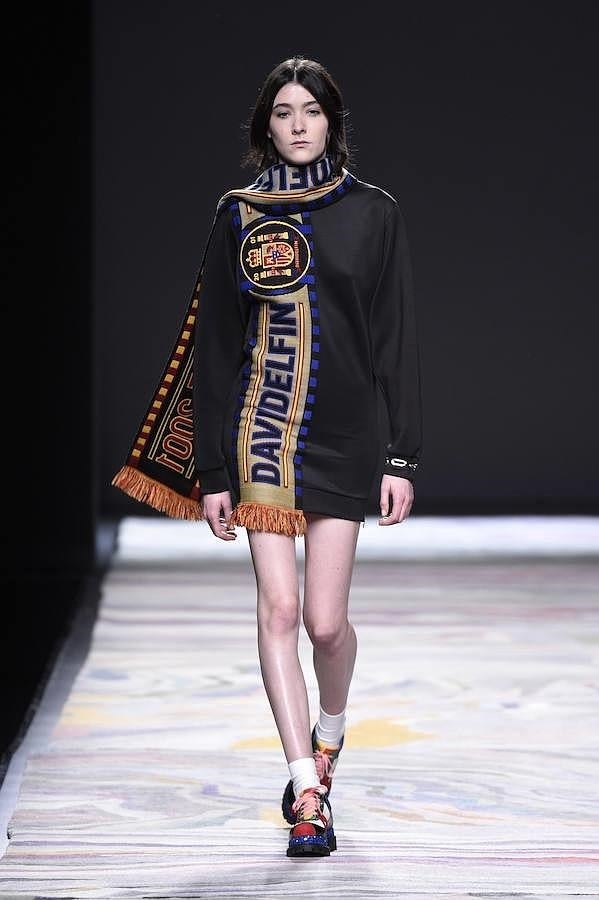 Vestido negro y bufanda con letras de la marca y escudo.