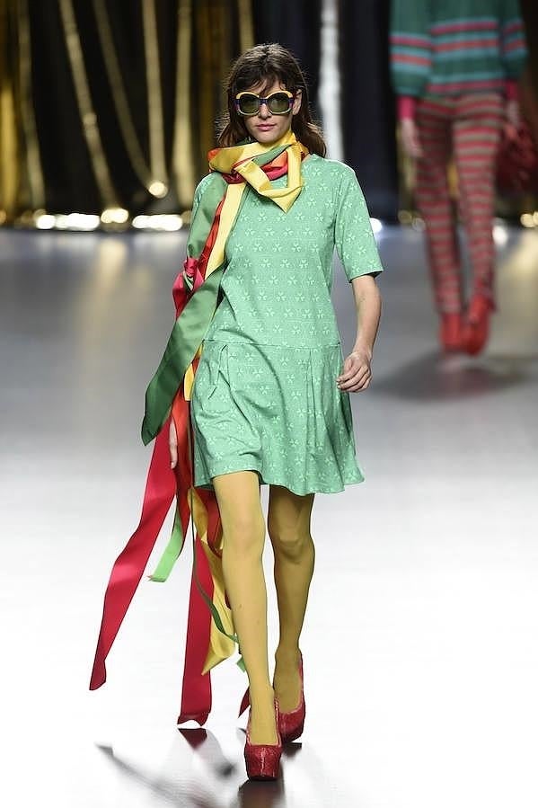 Vestido verde decorado con flores, medias amarillas y zapatos rojos.