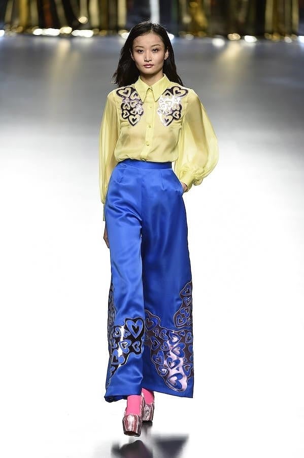 Pantalón azul de seda y blusa amarilla decorados con corazones plateados.