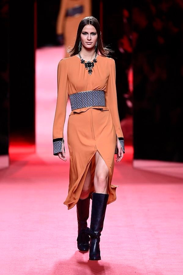 Falda y chaqueta naranja con puños y cinturón estampados.