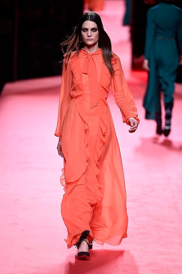 Vestido vaporoso de color naranja con volantes y lazada al cuello.