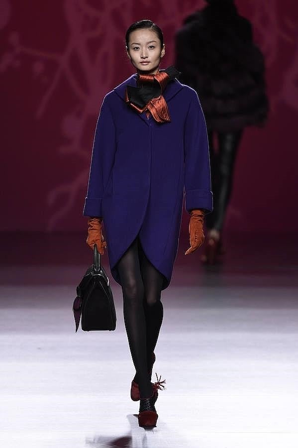 Abrigo morado combinado con medias negras y guantes naranjas.