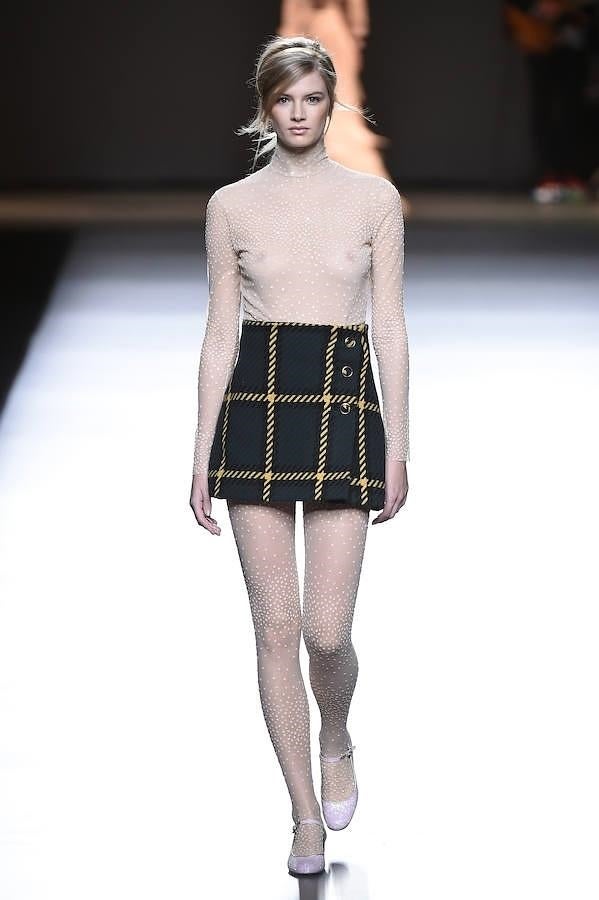 Minifalda de cuadros con jersey y medias de color nude.