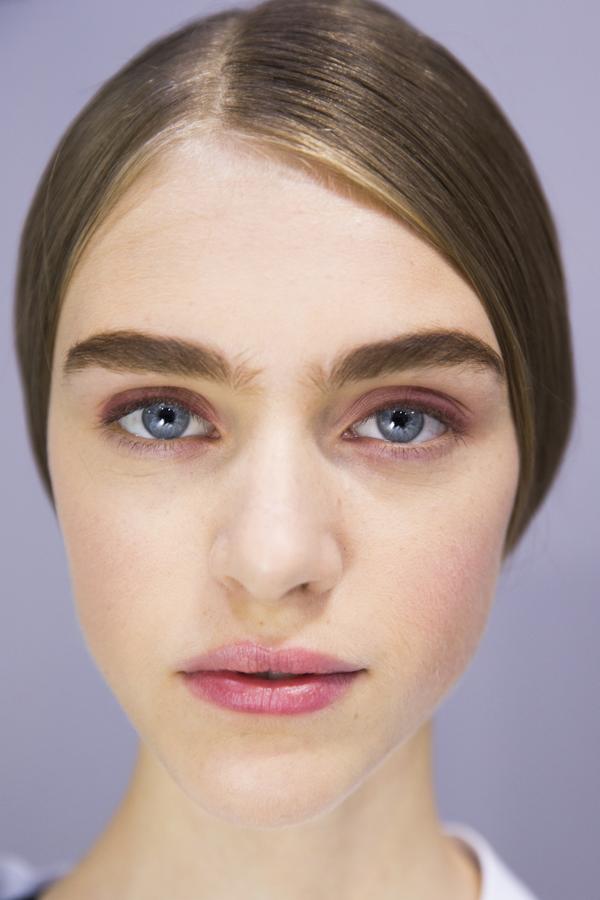 Look: Imagen pulcra y serena, con el pelo recogido detrás con raya semilateral. El maquillaje se interpreta en rosa, para labios, sombra de ojos y mejillas. Plus: Cejas largas y anchas que cobran protagonismo al ser maquilladas en marrón oscuro.