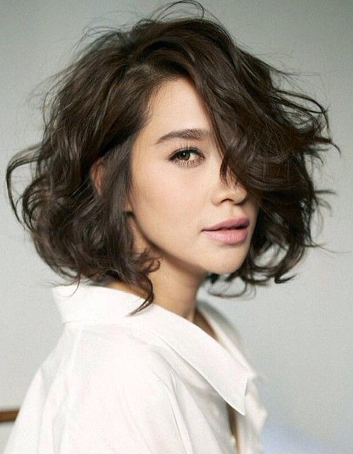 Media melena oscura con raya a un lado y ondas alborotadas por toda la cabeza que crean mucho volumen.