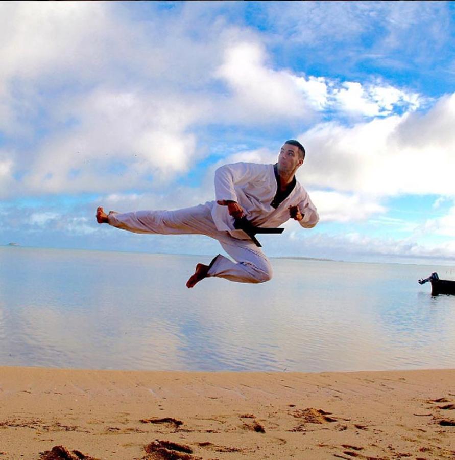 Pita Taufatofua en una imagen volando sobre la arena de la playa.