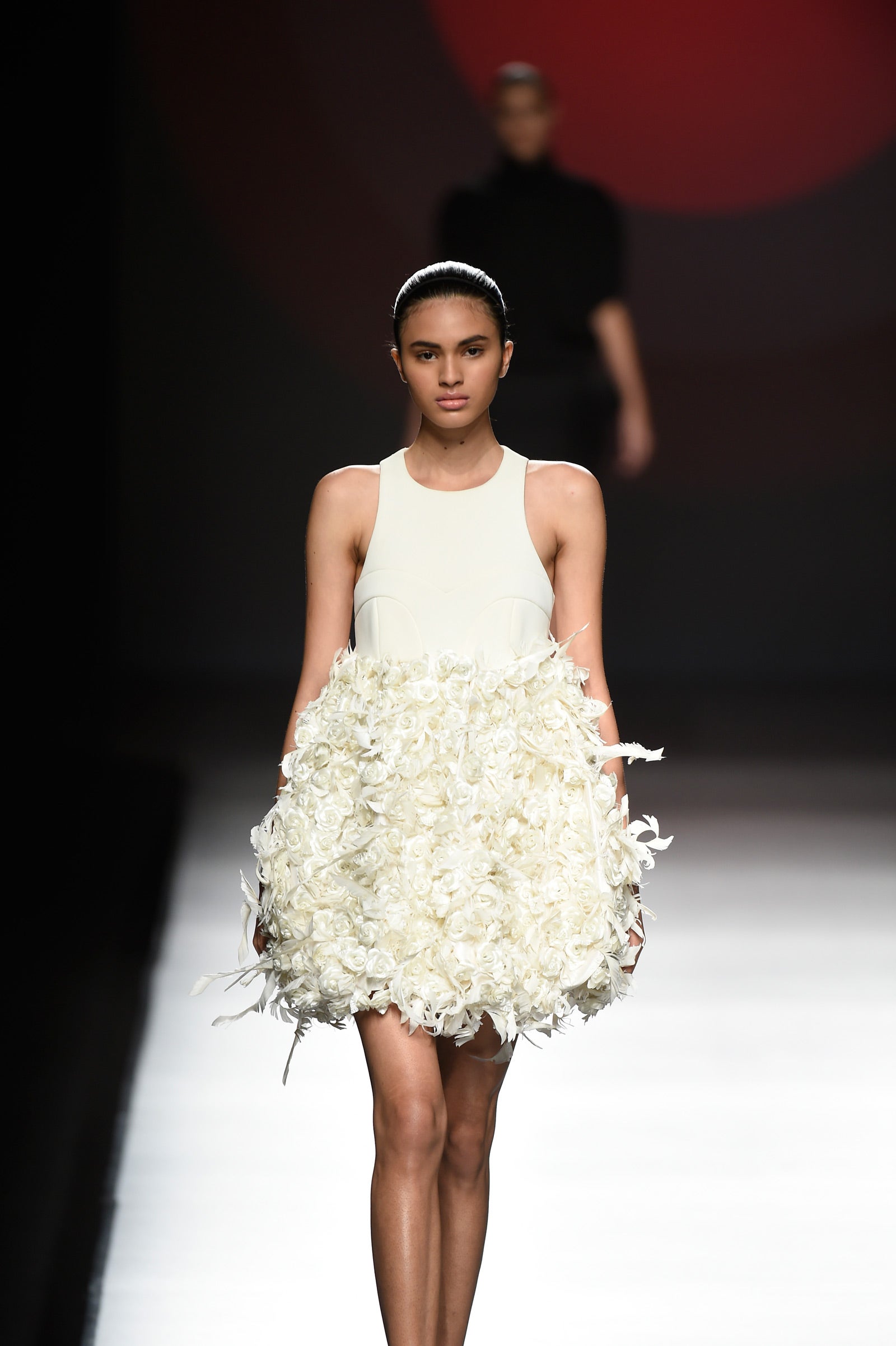 Vestido corto blnaco donde la falda está compuesto por plunas que simulan rosas.