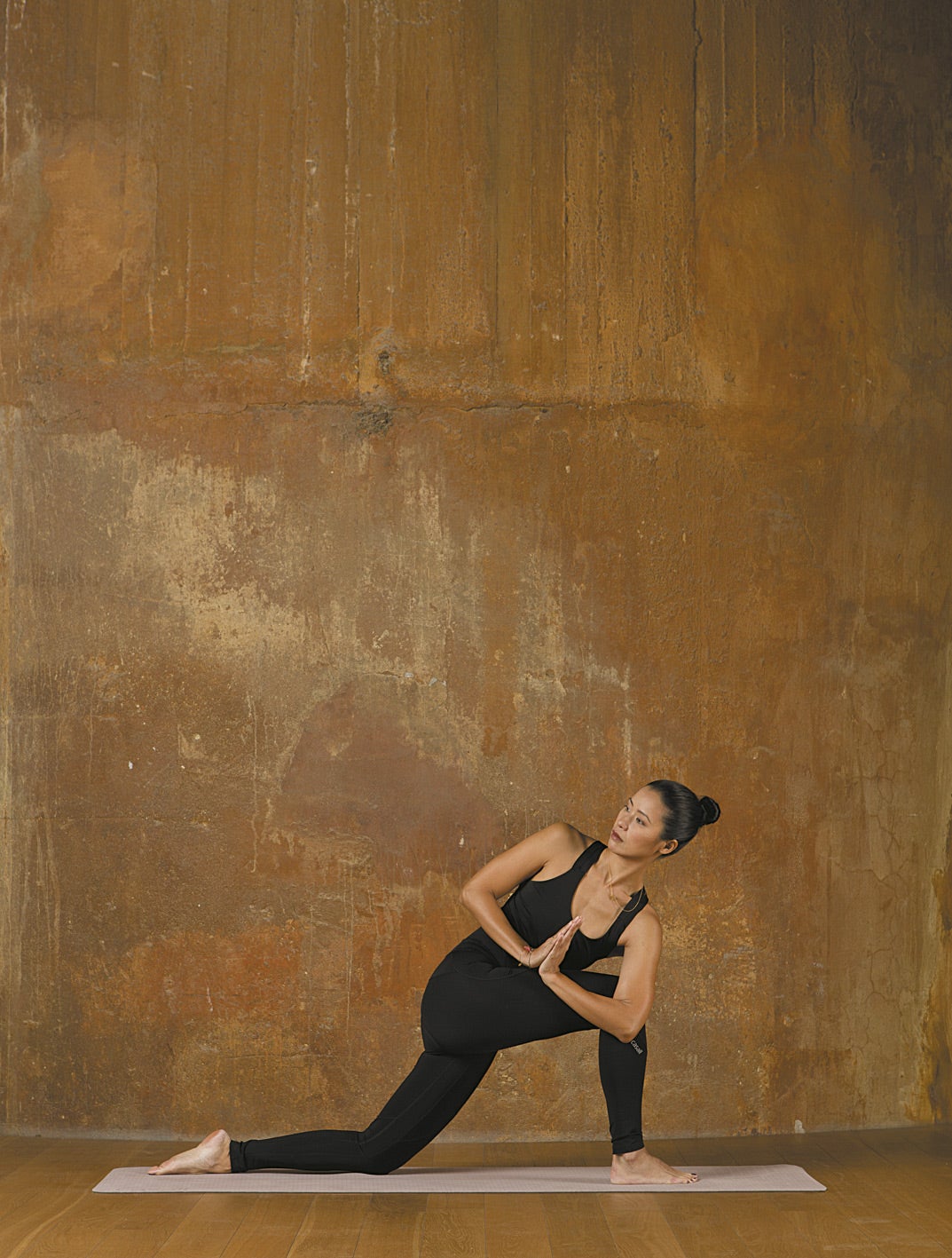 En torsión. De pie con los pies juntos, da un gran paso atrás con la pierna izquierda. Desciende la rodilla izquierda hasta el suelo y gira el torso hasta que quede encima de la rodilla derecha. Al inspirar, extiende el brazo izquierdo hacia arriba; y, al espirar, gira el tronco hacia la derecha hasta que el codo quede colocado en el exterior de la rodilla. Incrementa la torsión desde el ombligo y une las manos en el pecho presionando el codo contra la rodilla derecha. Palabra de experta. Gracias a esta torsión, estimularás todos los órganos abdominales.