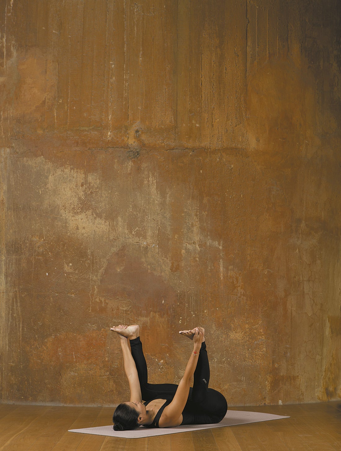 Placer infantil. Empieza estirada en el suelo boca arriba, dobla las rodillas y sujeta la planta de los pies con las manos, manteniendo toda la espalda pegada en el suelo. Acerca las rodillas a las axilas manteniendo las plantas de los pies hacia el techo. Si te resulta difícil, puedes usar un cinturón para agarrarte los pies. Mantén la postura durante cinco respiraciones. Palabra de experta. Esta postura libera la tensión de la espalda baja y el sacro, además de resultar muy relajante.