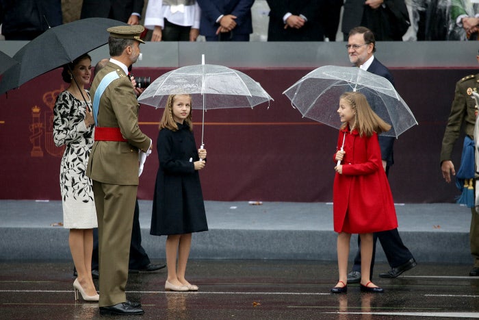 La Princesa Leonor mira atenta a sus padres durante el desfile pasado por agua del Día de la Hispanidad. ¿Estaría pensando, como cualquier niña, si saltar en un charco con su hermana?