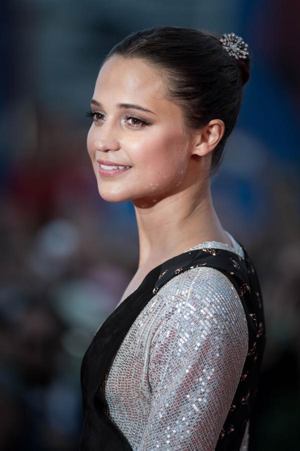 El moño de bailarina sienta fenomenal, es fácil de hacer y puedes adornarlo con un pasador como Alicia Vikander para que se convierta en un peinado 10 para Nochebuena. Háztelo con raya en el medio o sin raya, alto o bajo.