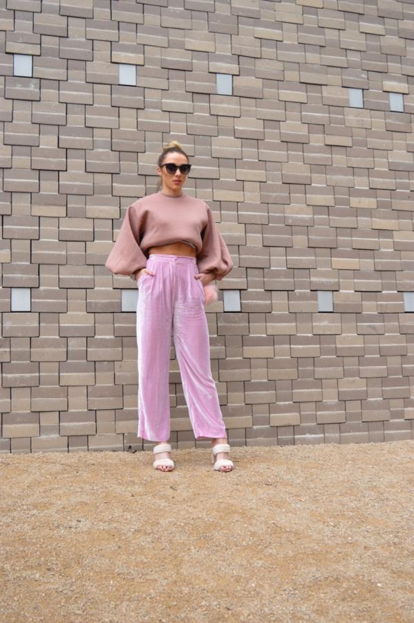 No abandana nuestros armarios, simplemente evoluciona para adaptarse a la nueva estación. Pantalón de terciopelo rosa, sudadera con manga de mariposa y sandalias de tacón beige.