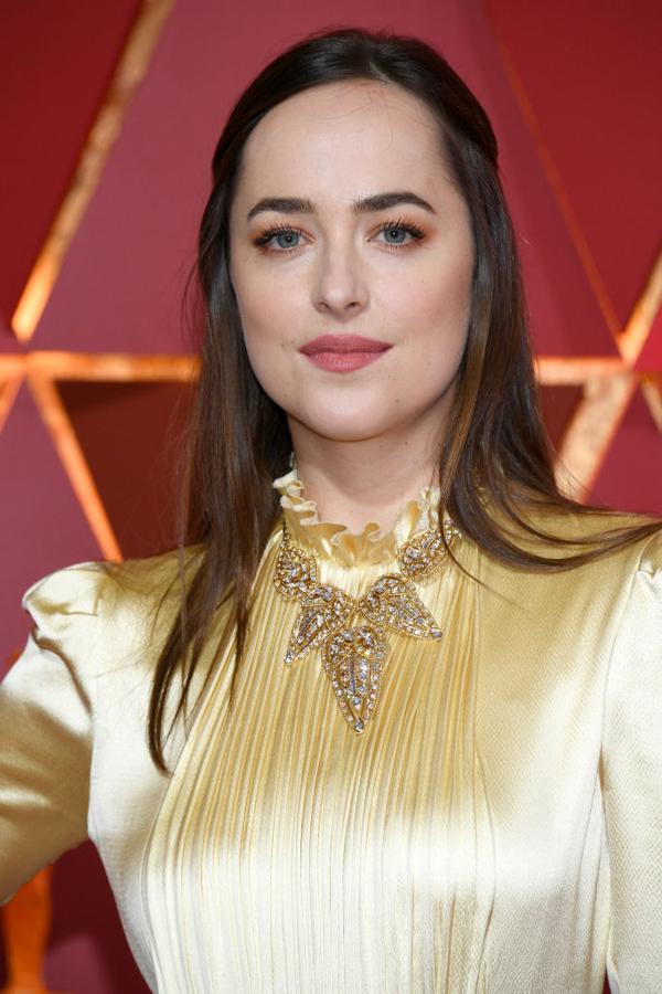Dakota Johnson lució su melena lisa semirrecogida que combinó con sombras en tono naranja, máscara de pestañas y labios melocotón.