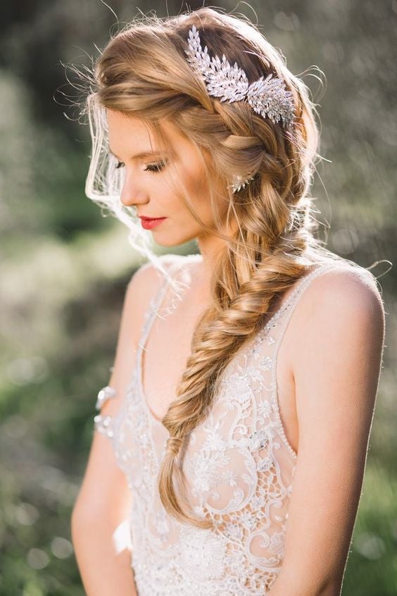 Las trenzas siguen siendo tendencia para las novias. Si buscas un look boho-chic o romántico, no pueden faltar las trenzas en tu peinado. En éste se combina una trenza de raíz ancha y semideshecha con una trenza de espiga. El pasador le aporta el toque nupcial perfecto a este peinado informal.