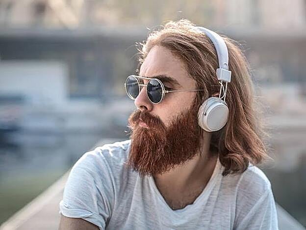 Foto de un hombre abstraído escuhcando música con sus auriculares