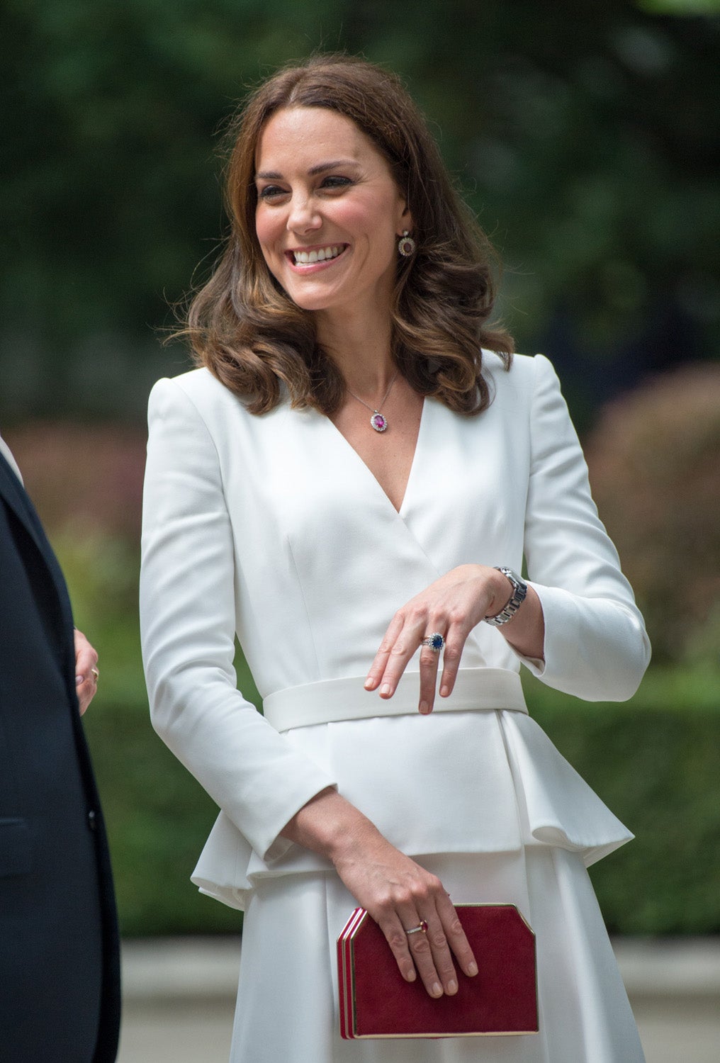 La duquesa de Cambridge ha optado por un dos piezas con falda de vuelo por encima de la rodilla y blusa con manga larga, escote en V y cinturón de color blanco. Un estilismo firmado por uno de sus diseñadores de cabecera, Alexander McQueen. Kate ha completado su look con zapatos nude y clutch rojo, y un conjunto de pendientes, colgante y sortija.