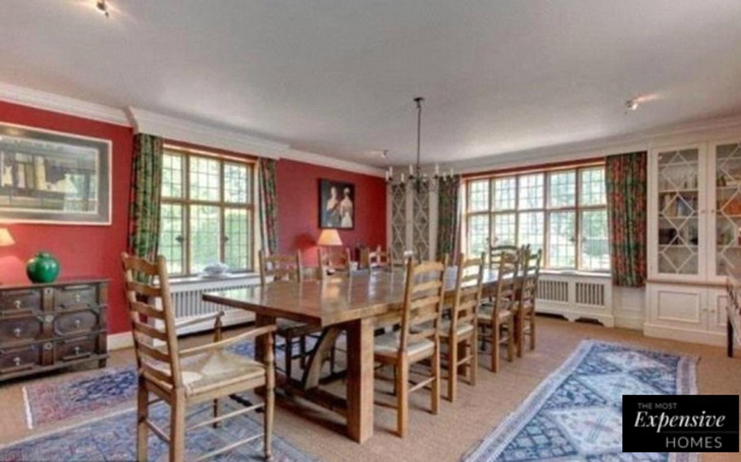 Imagen de uno de los comedores de la mansión, con la madera como protagonista, y una conjunción de muebles de inspiración colonial y rojo inglés en las paredes.