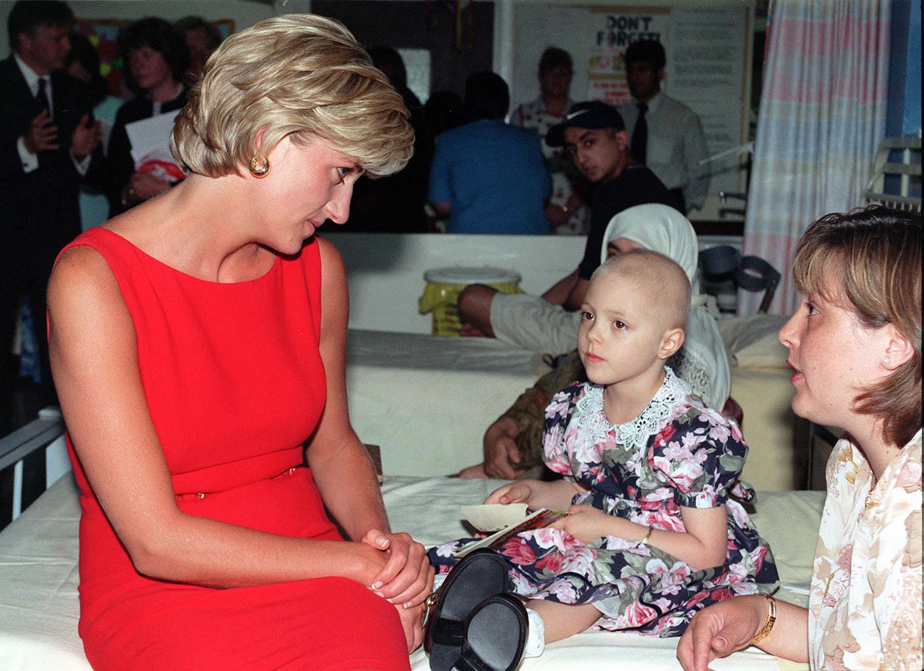 Diana de Gales con un vestido en color rojo y unos pequeños pendientes de aro en color dorado.