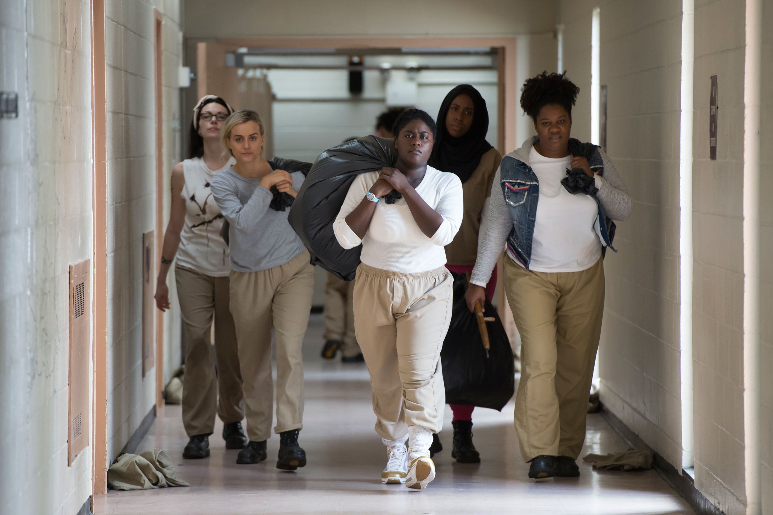 Las mujeres prontagonistas de la serie 'Orange is the new black' cargando unas bolsas en uno de los pasillos de la cárcel.