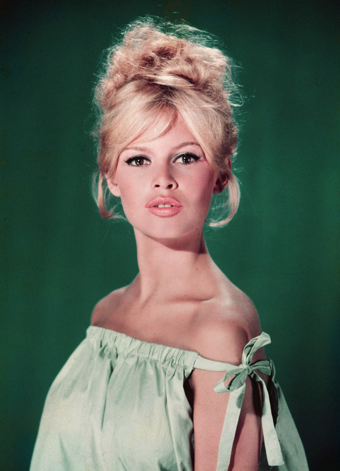 Uno de los flequillo más imitados es el de la francesa Brigitte Bardot. Aquí lo luce en cortinilla y con un moño alto tipo 'bun'.