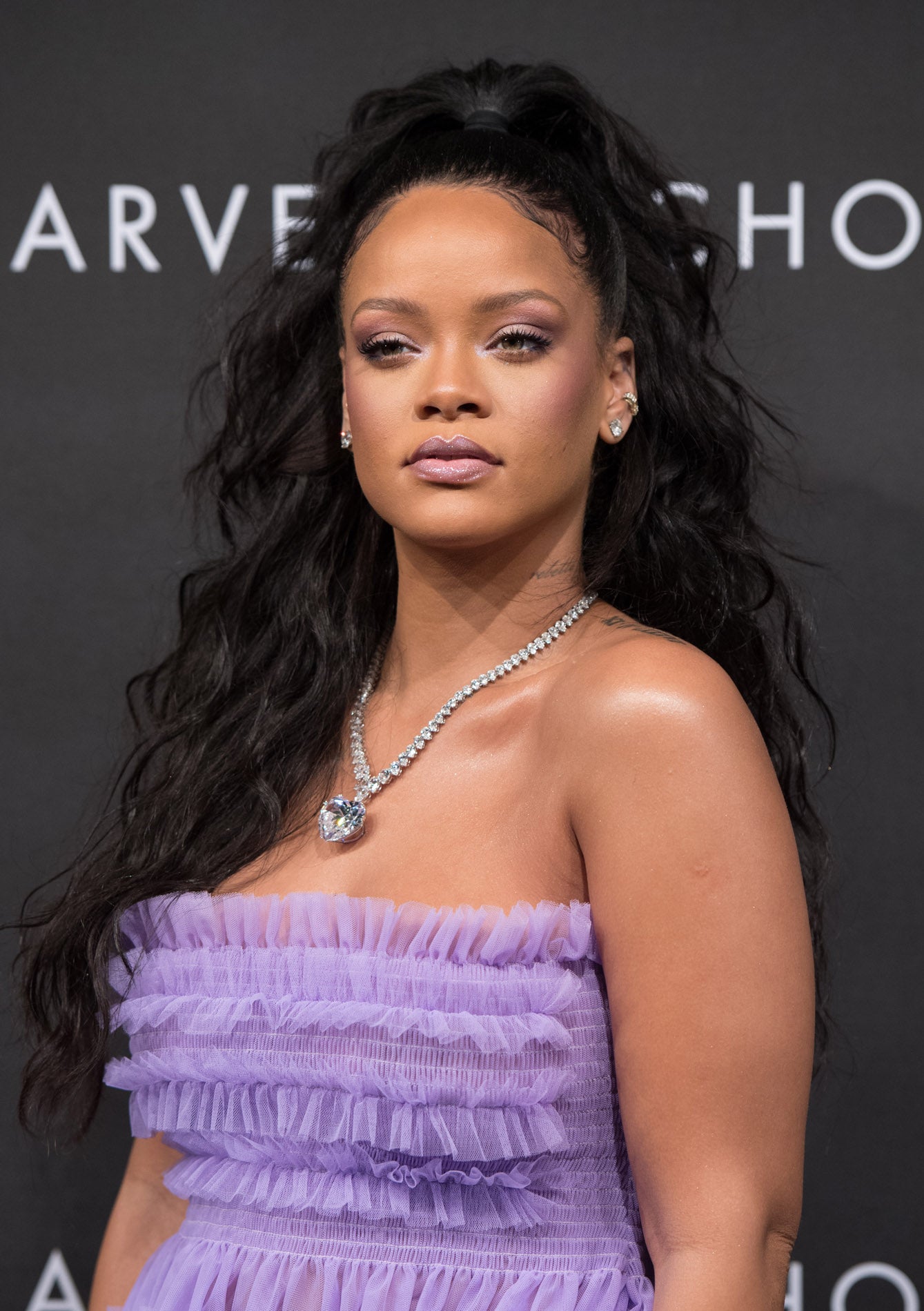 La cantante Rihanna con media coleta alta, con goma negra y melena XXL rizada.