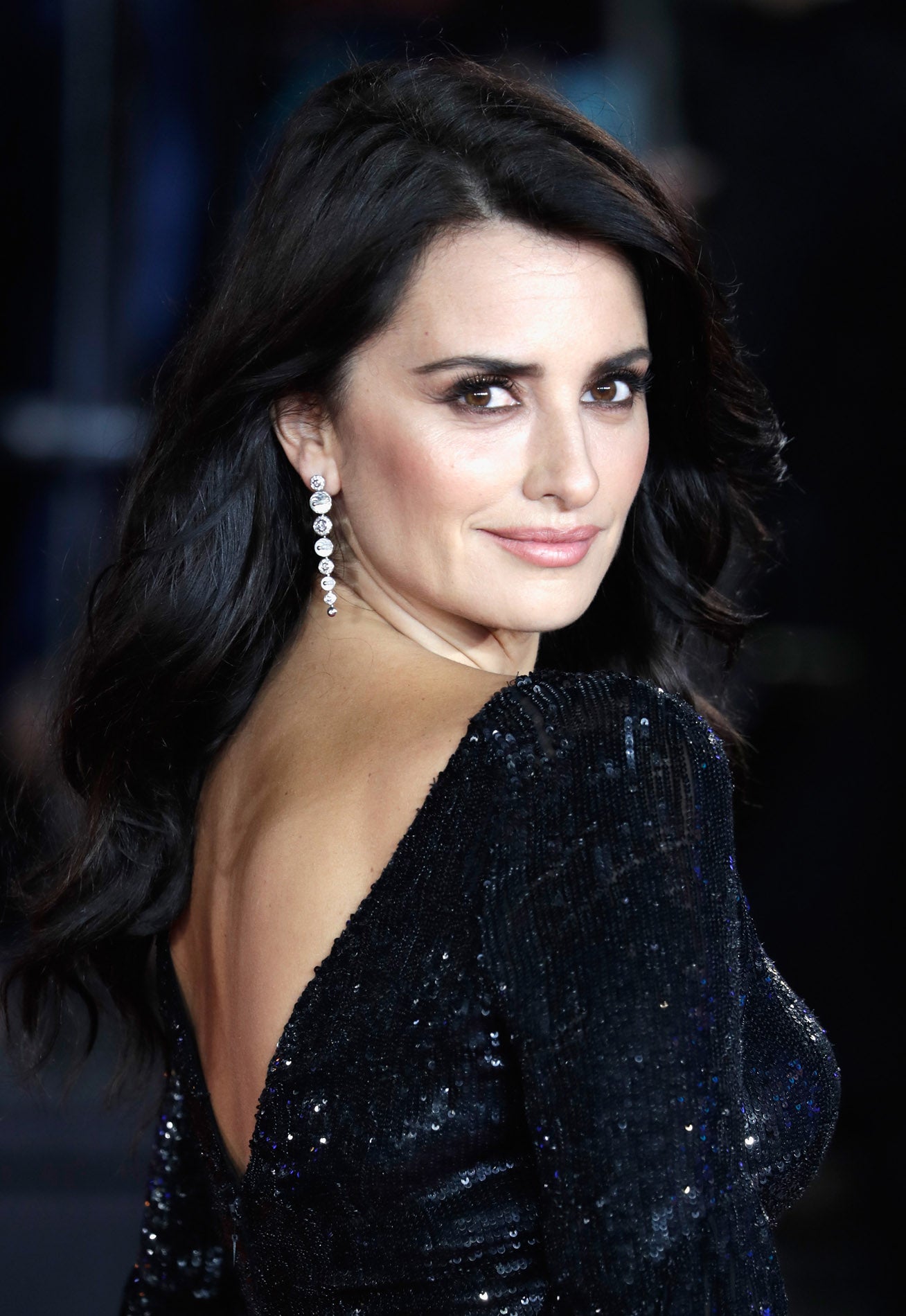 Si quieres dejarte la melena suelta, copia a Penélope Cruz y hazte unas ondas de medios a puntas, con raya a un lado para mantener apartado el pelo de las orejas y que se vean tus maxi pendientes.