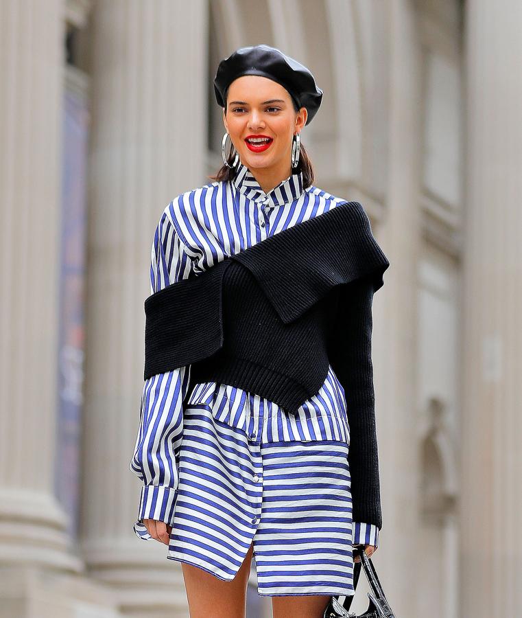 Kendall Jenner lleva puesto un vestido camisero blanco a rayas y un jersey negro. Su boina negra queda genial con el look que ha escogido.