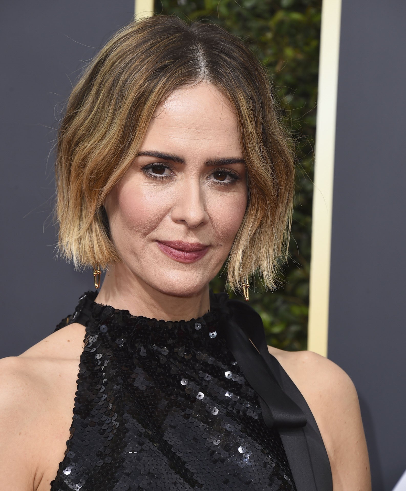 Sarah Paulson con un bob asimétrico con la nuca despejada y peinado con ondas suaves y raya en el medio.