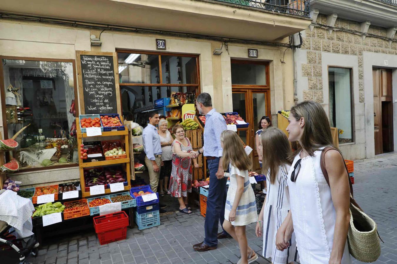 El Rey Felipe VI saluda a los dueños de una frutería durante un paseo en familia por las calles de la localidad mallorquina de Soller el pasado verano.