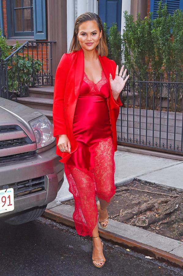 De la cama a la calle, Chrissy Teigen lució un vestido lencero de satén con encaje de Haney que combinó con una americana roja y unas sandalias de pulsera