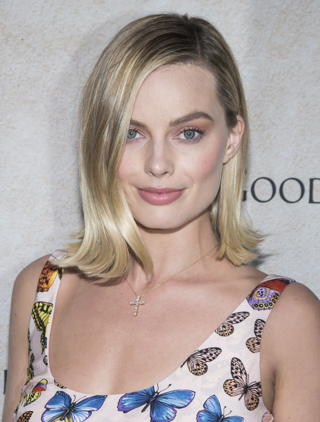 Margot Robbie con un look preppy, con la media melena lisa y las puntas hacia fuera, peinada con raya a un lado. Fíjate en cómo cambia el peinado, al poner la raya a uno u otro lado.