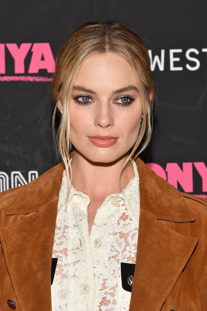 Margot Robbie con otro peinado perfecto para la media melena: un moño bajo con raya en el medio, mechones sueltos y las raíces pulidas.
