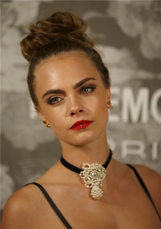 La modelo Cara Delevingne con un moño alto. Este peinado nos gusta mucho porque si le añades un maquillaje que consista en resaltar tus pestañas y tus labios, tendrás el look beauty perfecto.