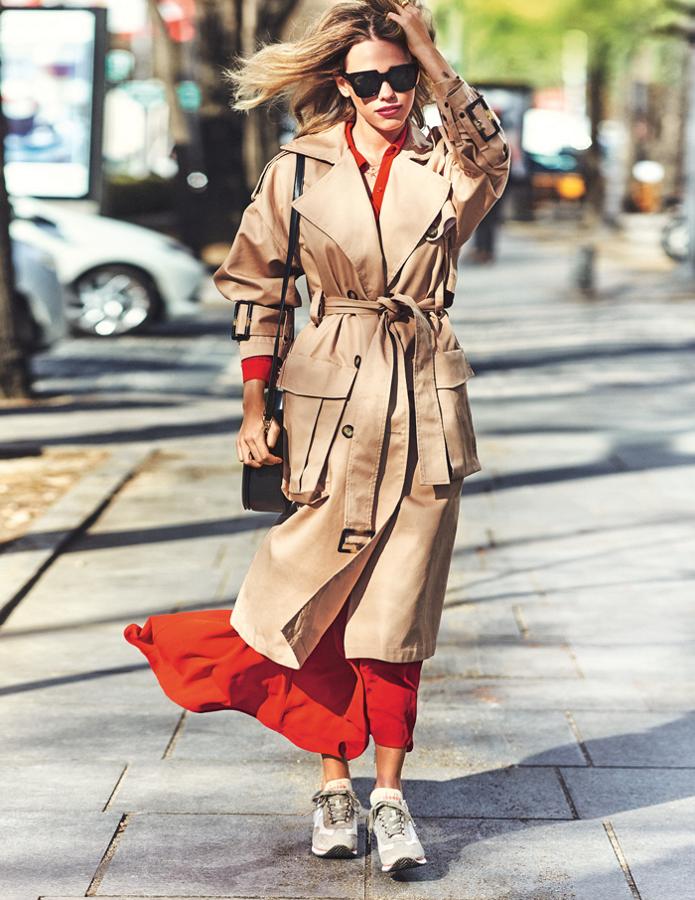 Almudena Lapique luce Gabardina de U de Adolfo Domínguez con un vestido rojo de Tintoretto para El Corte Inglés. Las deportivas son un diseño de Diadora; el bolso, de Salvatore Ferragamo. Gafas de sol, de Hawkers; anillo de Tous; y cadenas, de Aristocrazy.