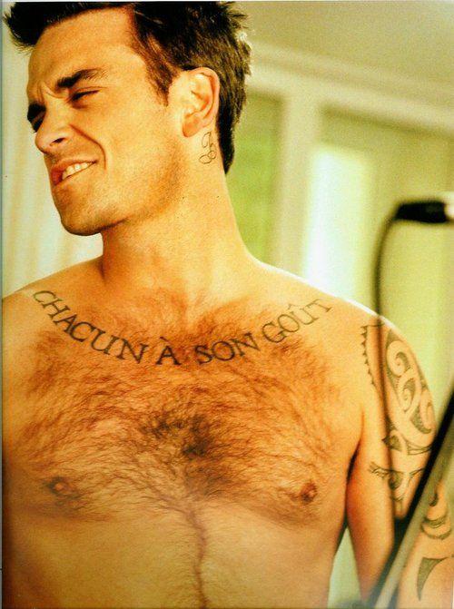 Robbie Williams con tatuajes en los brazos, hombros y torso.