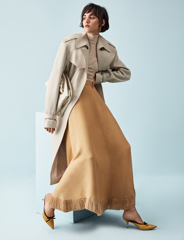 Trench, vestido y bolso de Céline, con body y falda de Nina Ricci. Pendientes, pulsera y anillo de Cartier y mules de Rochas.