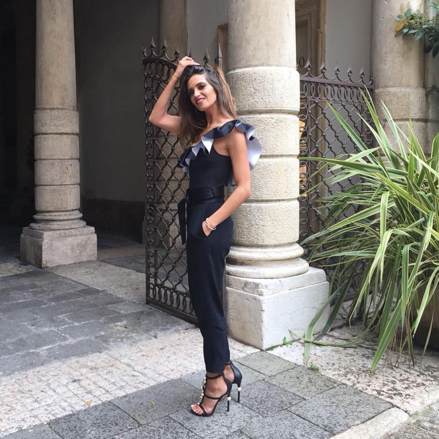 Sara Carbonero lució, a modo de body, este maravilloso bañador negro con escote asimétrico de volantes de la Special Edition de Calzedonia, y lo combinó con unos favorecedores pantalones de cintura marcada de Iro, originales sandalias joya de Elisabetta Franchi.