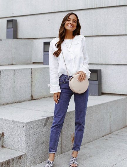 La influercer lleva unos pantalones vaqueros que combina con una blusa blanca abotonada y unas sandalias con tiras cruzadas. ¡Y el bolso redondo que no falte!