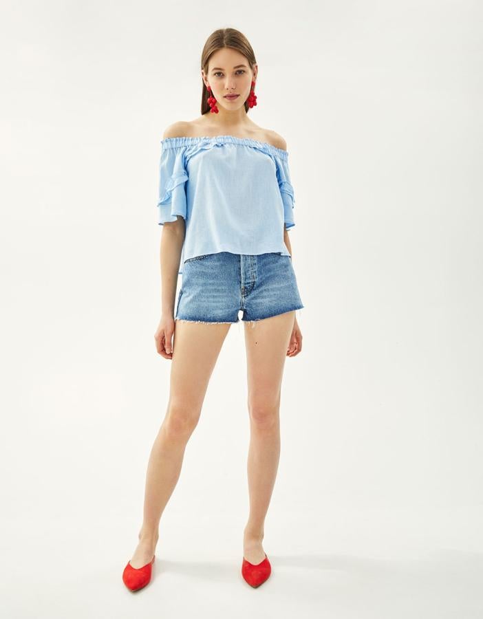 Camisa mesonera de lino en color azul claro y con volantes en escote y mangas, 12,99 euros.